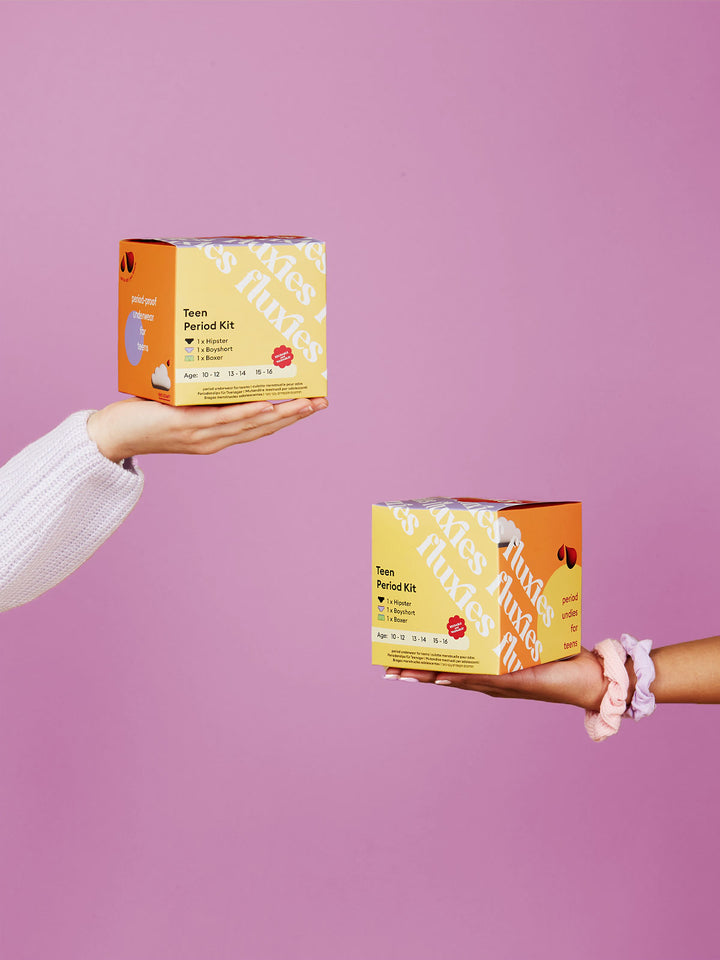 hands holding two boxes of teen period kit 