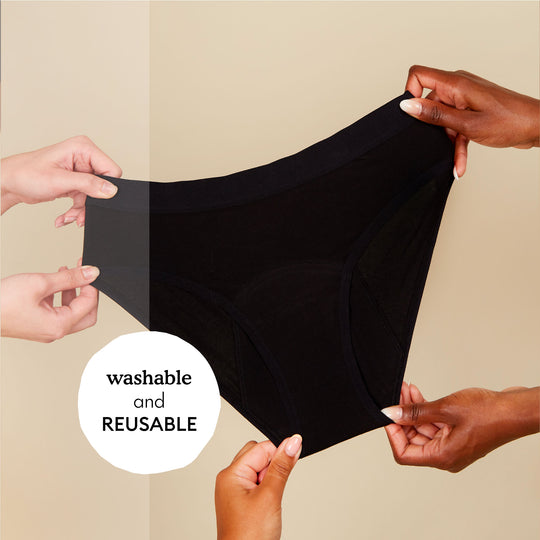 multiple hands holding a pair of period underwear with text reusable and washable