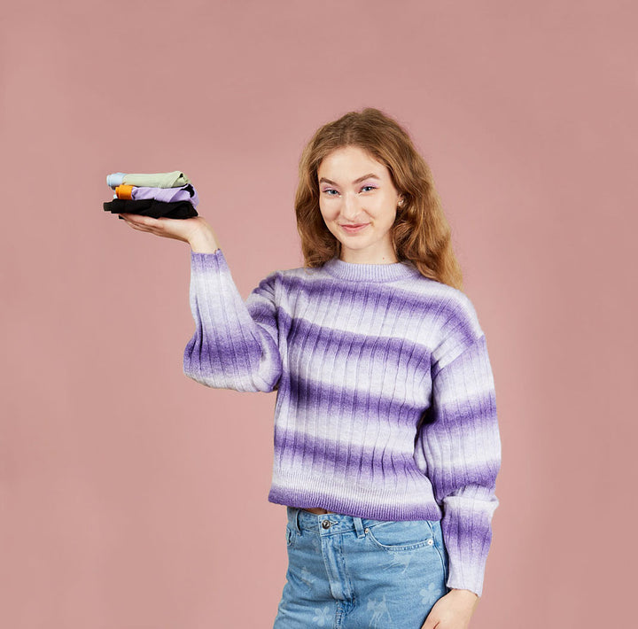 young teen smiling holding three pairs of fluxies period proof underwear in her hand